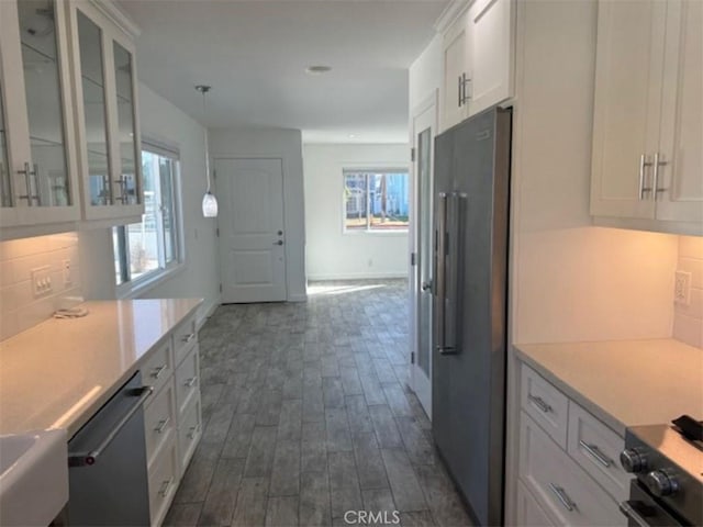 kitchen with appliances with stainless steel finishes, backsplash, dark hardwood / wood-style floors, white cabinetry, and hanging light fixtures