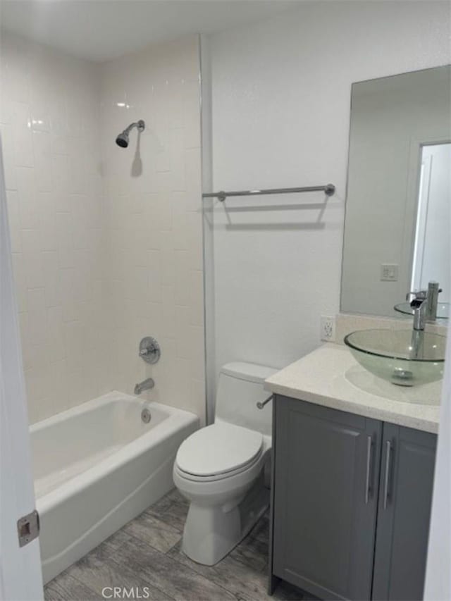 full bathroom with hardwood / wood-style flooring, tiled shower / bath combo, toilet, and vanity