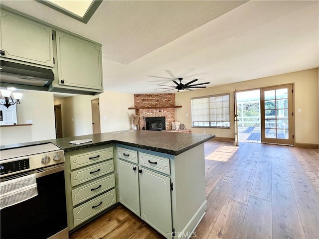 kitchen with extractor fan, a fireplace, kitchen peninsula, green cabinets, and stove