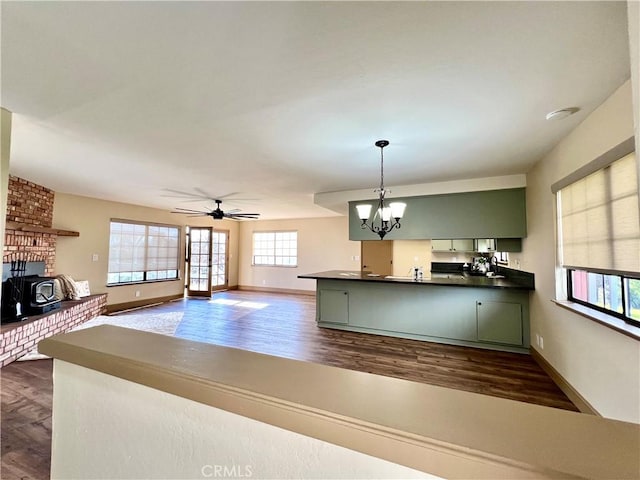 kitchen with ceiling fan with notable chandelier, a wood stove, hanging light fixtures, and green cabinetry