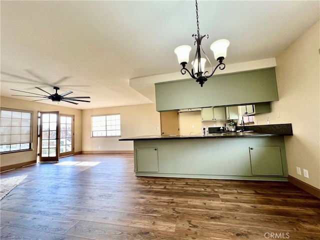 kitchen with hanging light fixtures, kitchen peninsula, ceiling fan with notable chandelier, and green cabinetry