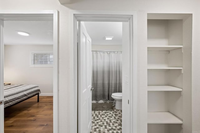 bathroom with hardwood / wood-style floors, built in features, toilet, and curtained shower