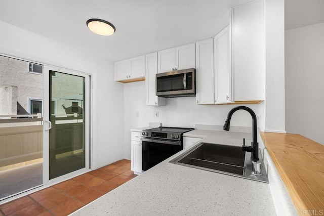 kitchen featuring appliances with stainless steel finishes, sink, light tile patterned floors, and white cabinets