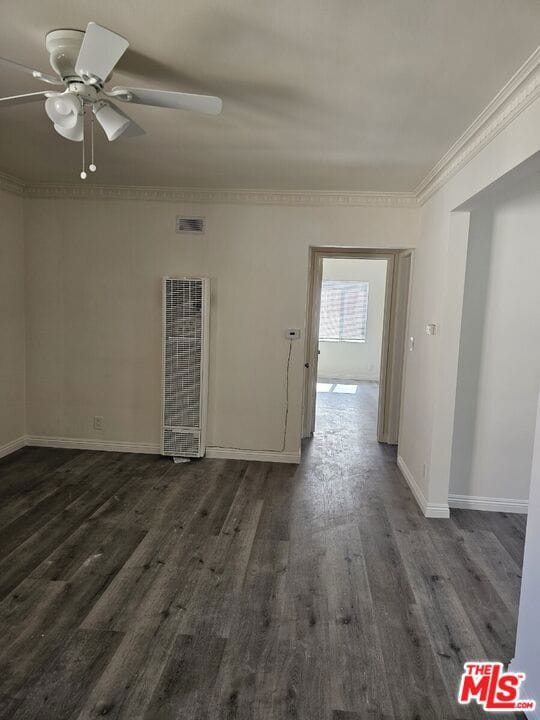 spare room featuring crown molding, ceiling fan, and dark wood-type flooring