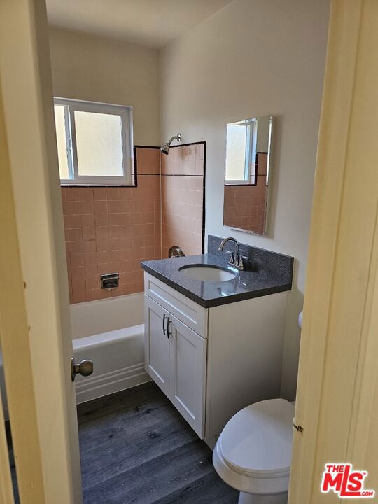 full bathroom with hardwood / wood-style floors, toilet, vanity, and a healthy amount of sunlight