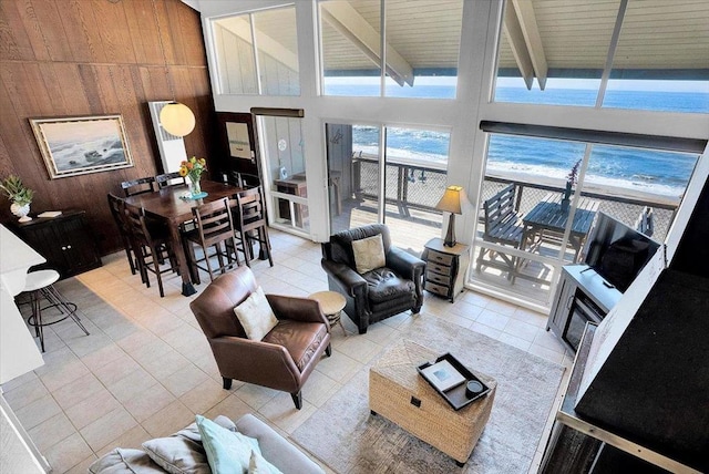 living room featuring light tile patterned flooring, beam ceiling, high vaulted ceiling, and wood walls