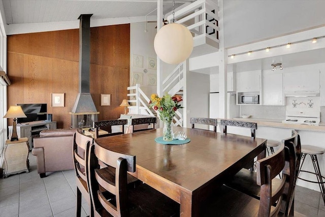 dining room with lofted ceiling, light tile patterned floors, and a wood stove