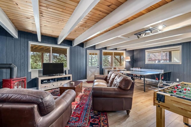 living room with wood ceiling, beam ceiling, light hardwood / wood-style flooring, a wood stove, and wood walls