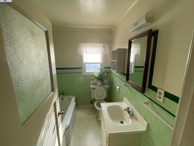 bathroom featuring vanity, a washtub, tile walls, ornamental molding, and toilet