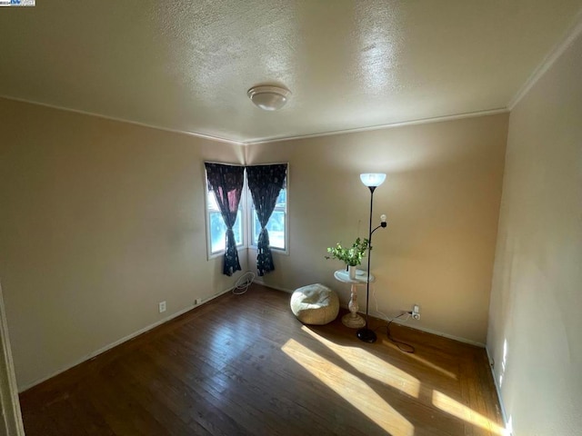 unfurnished room with wood-type flooring, a textured ceiling, and crown molding