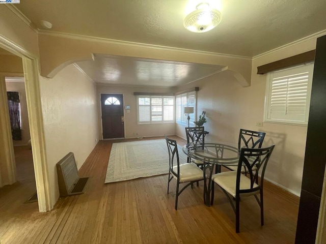 dining space featuring wood-type flooring and ornamental molding