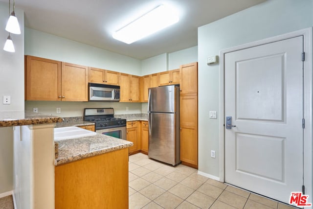 kitchen with light tile patterned floors, hanging light fixtures, stone countertops, and appliances with stainless steel finishes