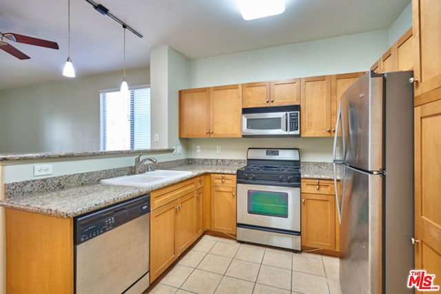 kitchen with ceiling fan, sink, stainless steel appliances, light stone counters, and pendant lighting