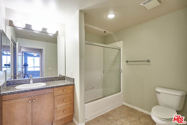 full bathroom featuring shower / bath combination with glass door, tile patterned floors, vanity, and toilet