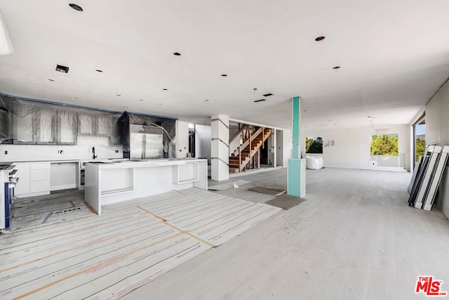 kitchen featuring white cabinets, a center island, appliances with stainless steel finishes, a kitchen bar, and light hardwood / wood-style flooring