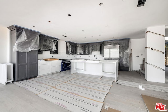 kitchen with a center island, a kitchen bar, high end appliances, sink, and light wood-type flooring