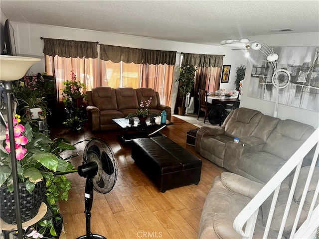 living room with ceiling fan, hardwood / wood-style flooring, and a textured ceiling