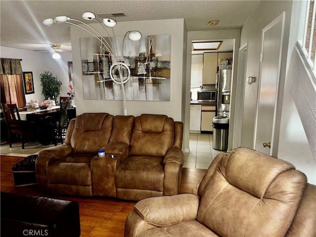 living room featuring ceiling fan, a textured ceiling, and hardwood / wood-style floors