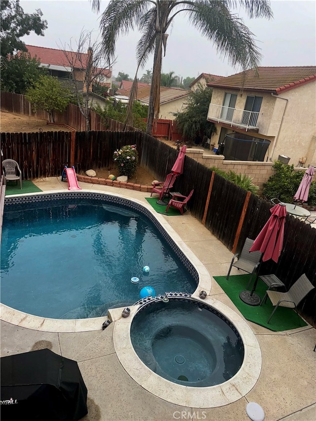 view of pool featuring a patio area and an in ground hot tub