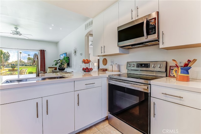 kitchen featuring appliances with stainless steel finishes, sink, light tile patterned floors, and white cabinetry