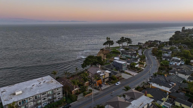 aerial view at dusk featuring a water view