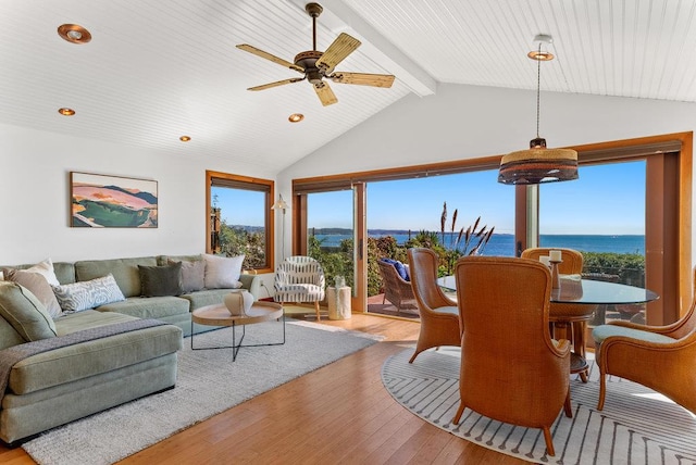 living room featuring vaulted ceiling with beams, light wood-type flooring, ceiling fan, and a water view