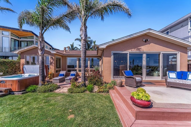 rear view of house featuring a yard, a hot tub, a patio, and outdoor lounge area