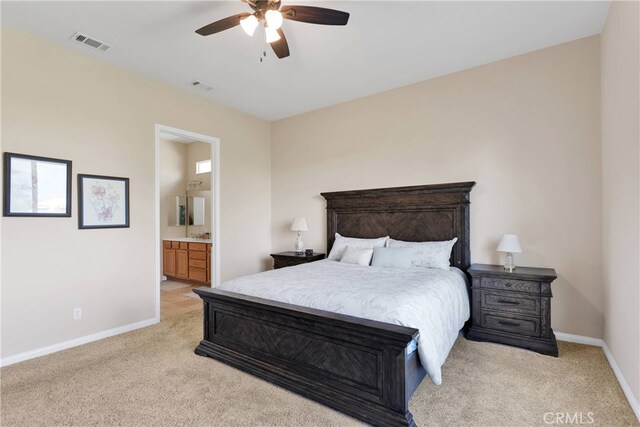 bedroom with ceiling fan, light carpet, and ensuite bath