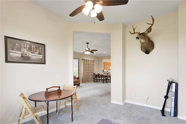 dining area with ceiling fan and light carpet