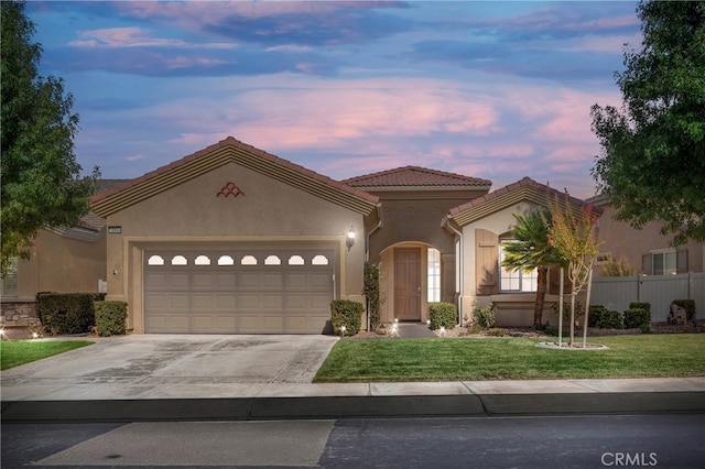 mediterranean / spanish-style home featuring a lawn and a garage