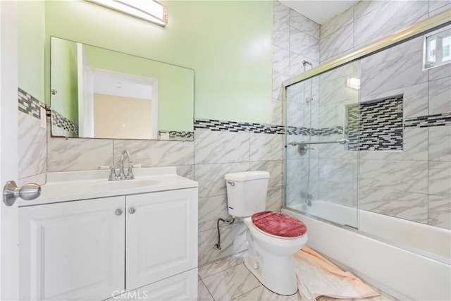 full bathroom with vanity, tile walls, toilet, and enclosed tub / shower combo