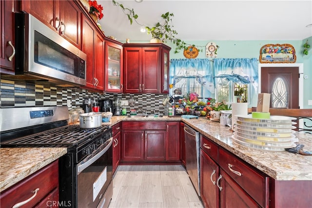 kitchen with light stone countertops, appliances with stainless steel finishes, sink, and decorative backsplash