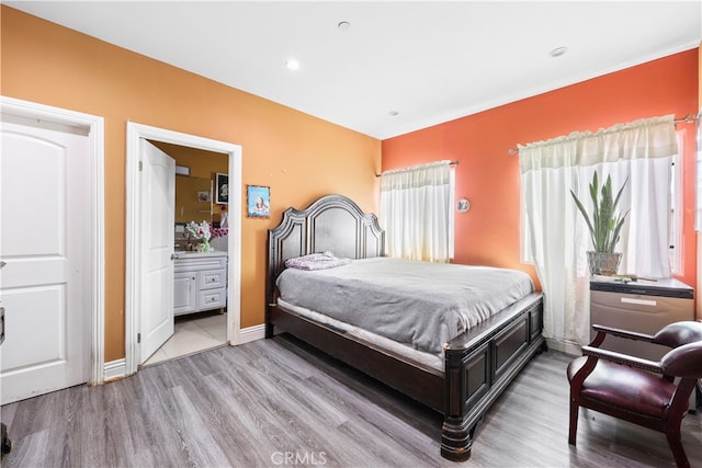 bedroom with ensuite bath and light hardwood / wood-style flooring