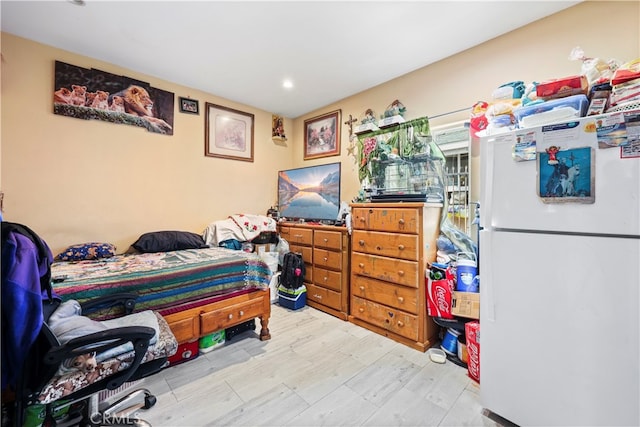 bedroom with white refrigerator and light hardwood / wood-style floors