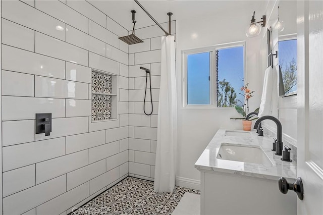 bathroom featuring double vanity, a wealth of natural light, a tile shower, and a sink