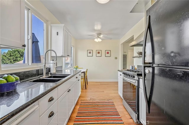 kitchen featuring light hardwood / wood-style floors, black fridge, white cabinetry, and stainless steel range with gas stovetop