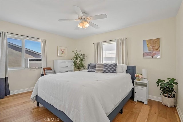 bedroom featuring light wood-type flooring, a ceiling fan, baseboards, and cooling unit