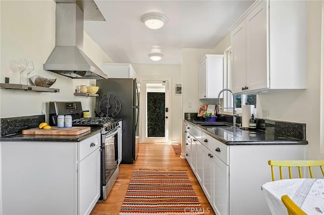 kitchen with light wood-style floors, white cabinetry, a sink, gas range, and wall chimney exhaust hood