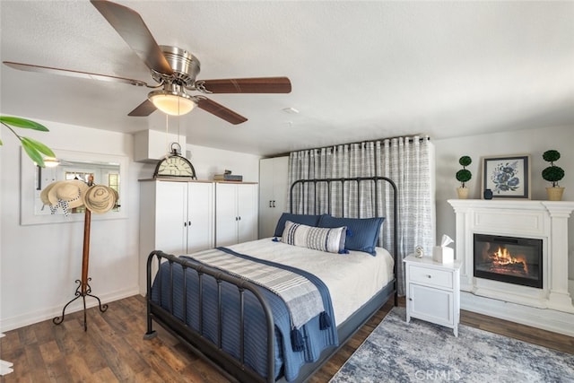 bedroom with ceiling fan, dark wood-type flooring, and a textured ceiling