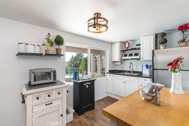 kitchen featuring white cabinets, sink, decorative backsplash, dark hardwood / wood-style flooring, and stainless steel refrigerator