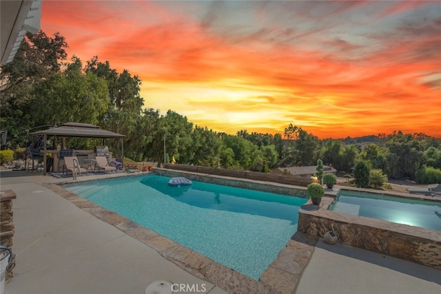 pool at dusk with a gazebo and a patio area