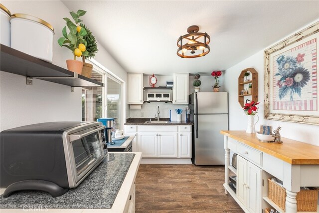 kitchen featuring backsplash, dark wood-type flooring, sink, white cabinetry, and stainless steel refrigerator