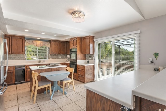 kitchen with light tile patterned floors, black double oven, and tasteful backsplash