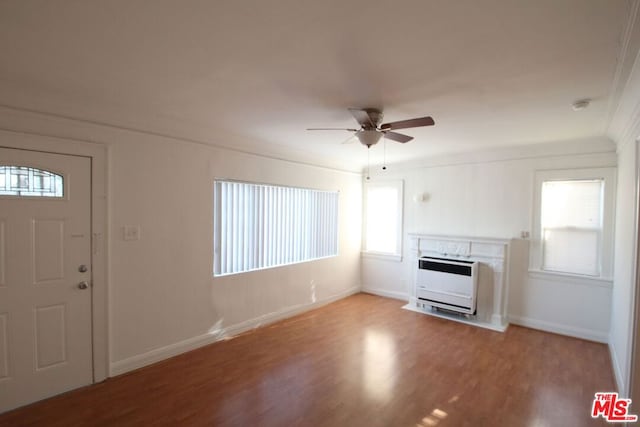 unfurnished living room featuring a fireplace, wood-type flooring, heating unit, and a healthy amount of sunlight