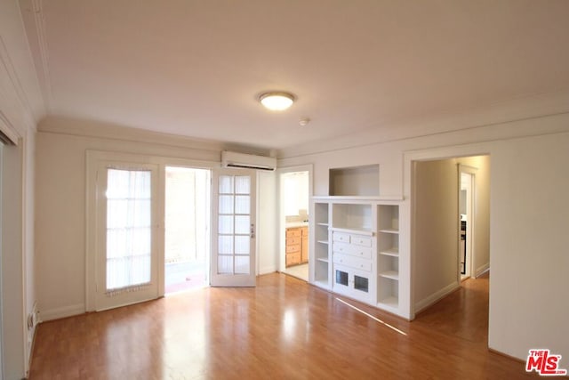 empty room featuring hardwood / wood-style flooring, ornamental molding, and an AC wall unit