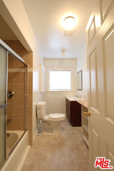 full bathroom with vanity, toilet, and combined bath / shower with glass door