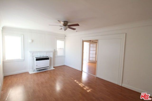 unfurnished living room with wood-type flooring, heating unit, crown molding, and ceiling fan