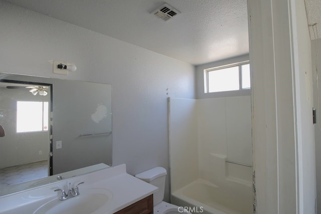 full bathroom featuring vanity, plenty of natural light, toilet, and a textured ceiling