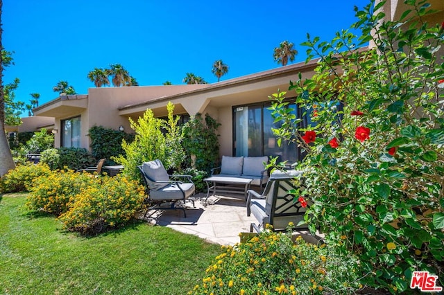 rear view of property with outdoor lounge area, a yard, and a patio