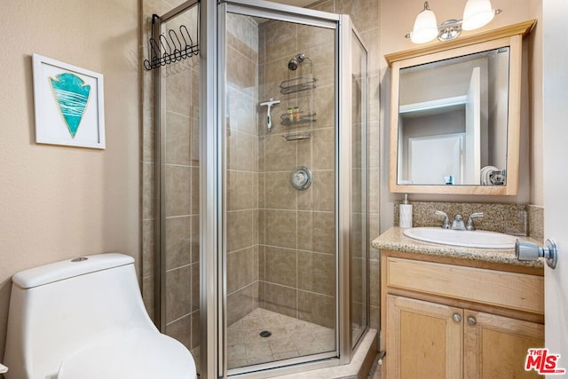 bathroom featuring a shower with shower door, vanity, and toilet